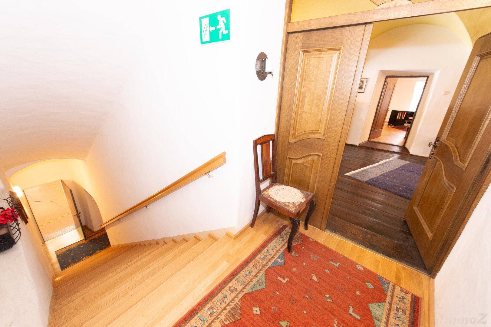 Holztreppe mit Teppichläufer und Holztüren, führt zu weiteren Räumen im Obergeschoss.