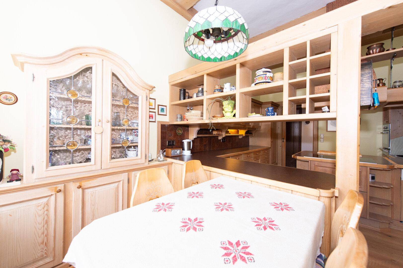 Essbereich in der Holzküche mit traditionellen Stühlen und einem großen Schrank, sehr einladend.