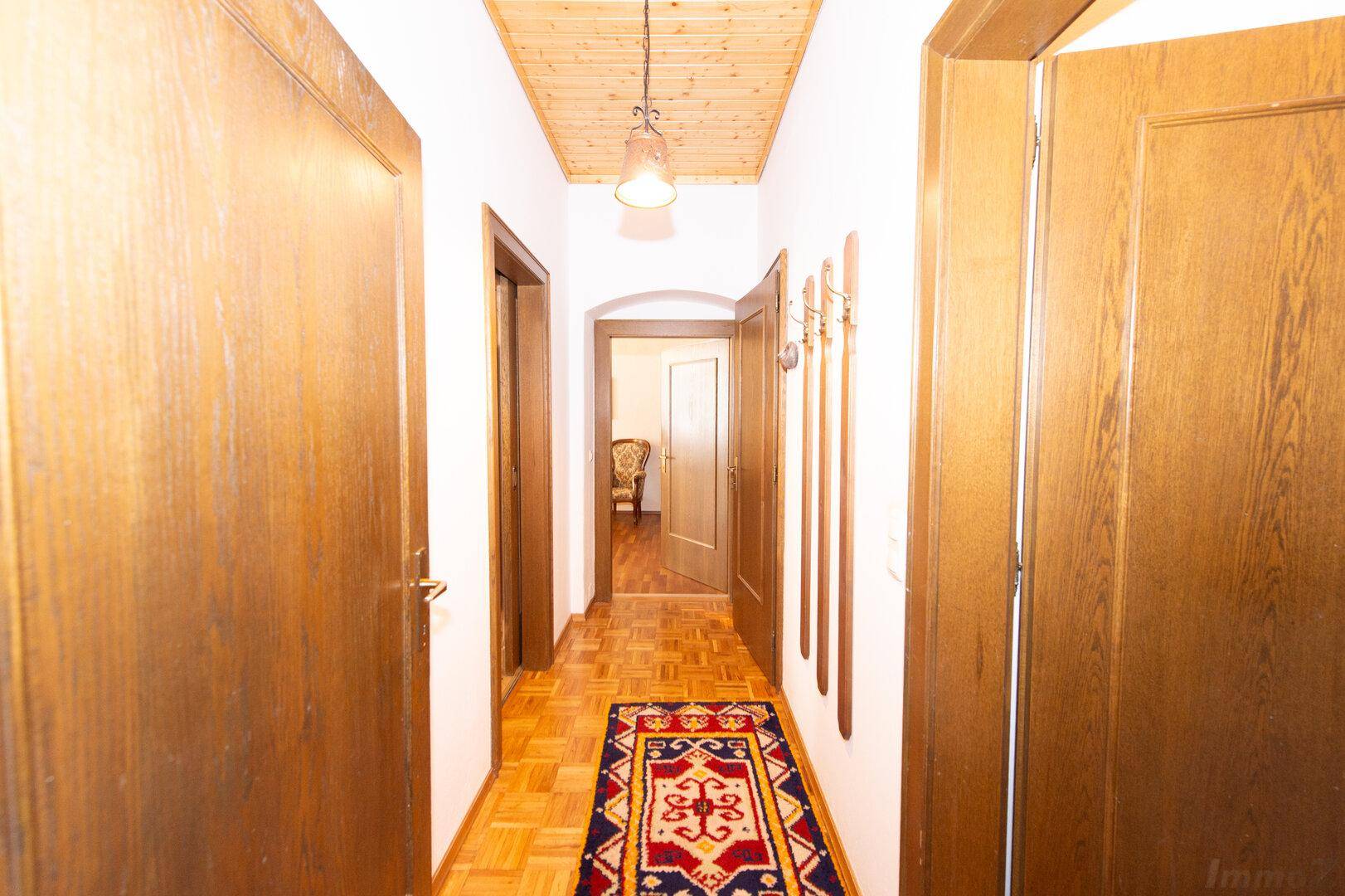 Heller Flur mit Holzboden und Holztüren, führt zu verschiedenen Räumen im Haus.