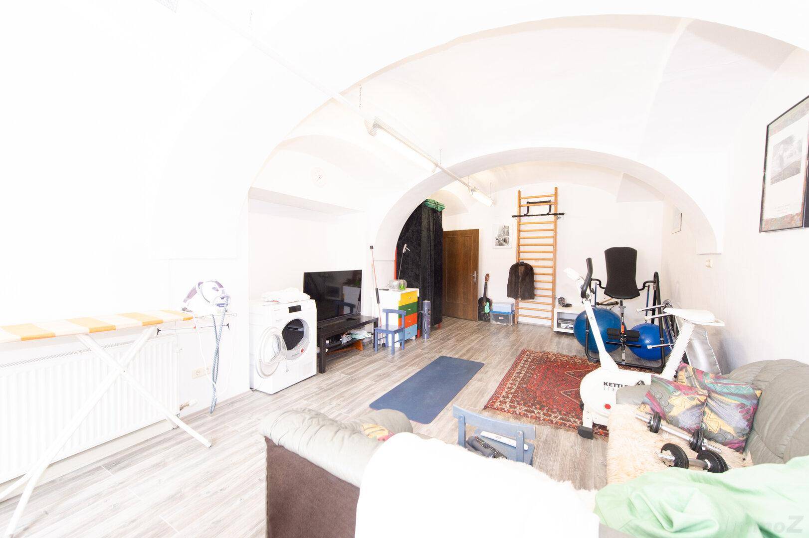 Großer Raum mit gewölbter Decke, Holzboden und verschiedenen Fitnessgeräten, vielseitig nutzbar.