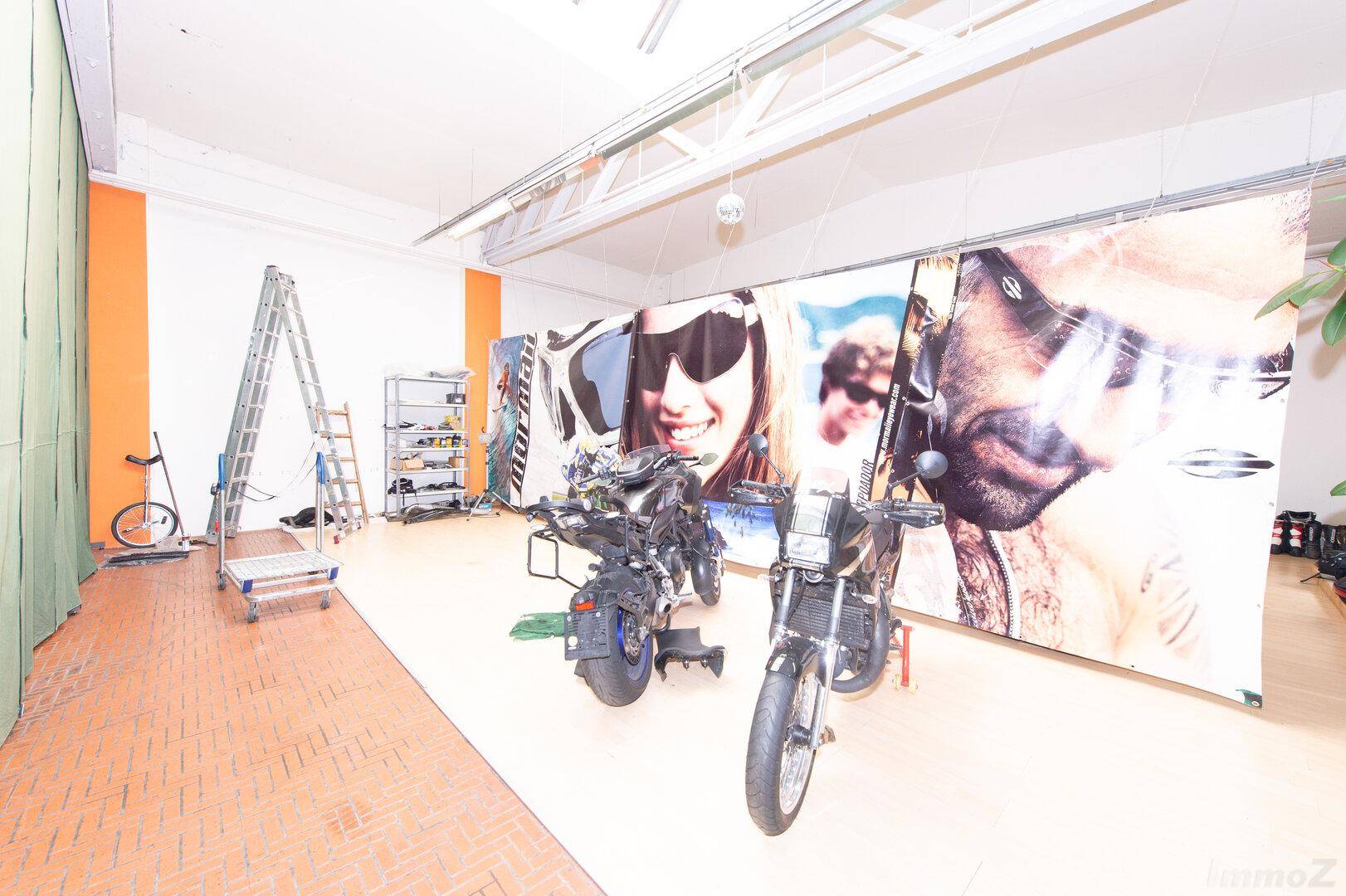 Geräumiger Ausstellungsraum mit Motorrädern und großformatigen Werbeplakaten an den Wänden.