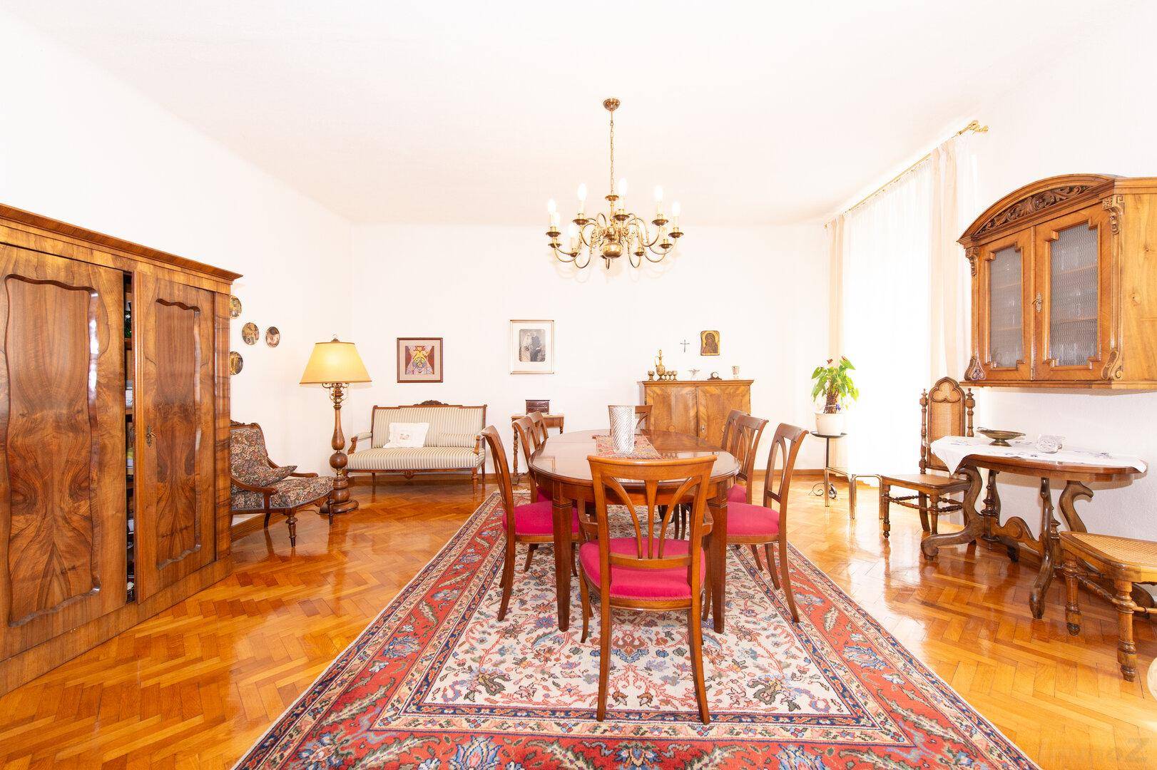 Eleganter Essbereich mit Holzboden, Kronleuchter und antiken Holzmöbeln, sehr repräsentativ.
