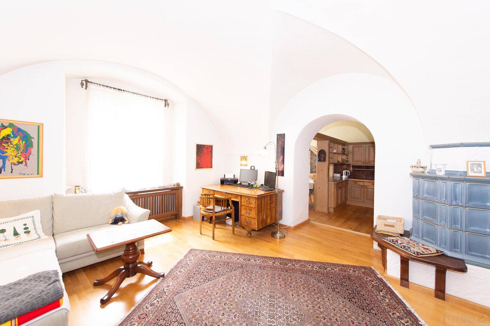 Wohnzimmer mit gewölbter Decke, Holzboden und einem traditionellen Kachelofen, sehr charmant.