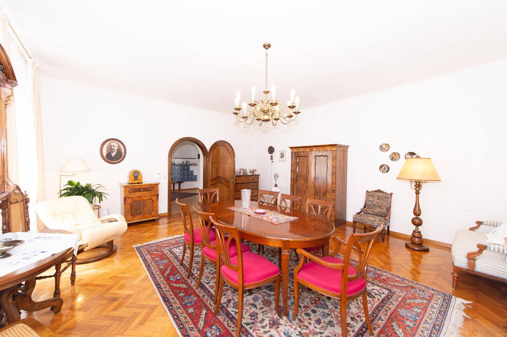 Geräumiger Essbereich mit traditionellen Holzmöbeln, einem Kronleuchter und Fischgrätparkettboden.