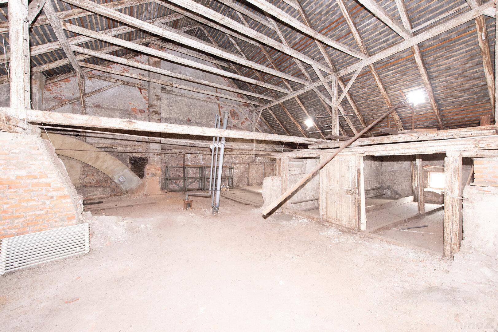 Unausgebauter Dachboden mit sichtbaren Holzbalken und Ziegelwänden, bietet Ausbaupotenzial.