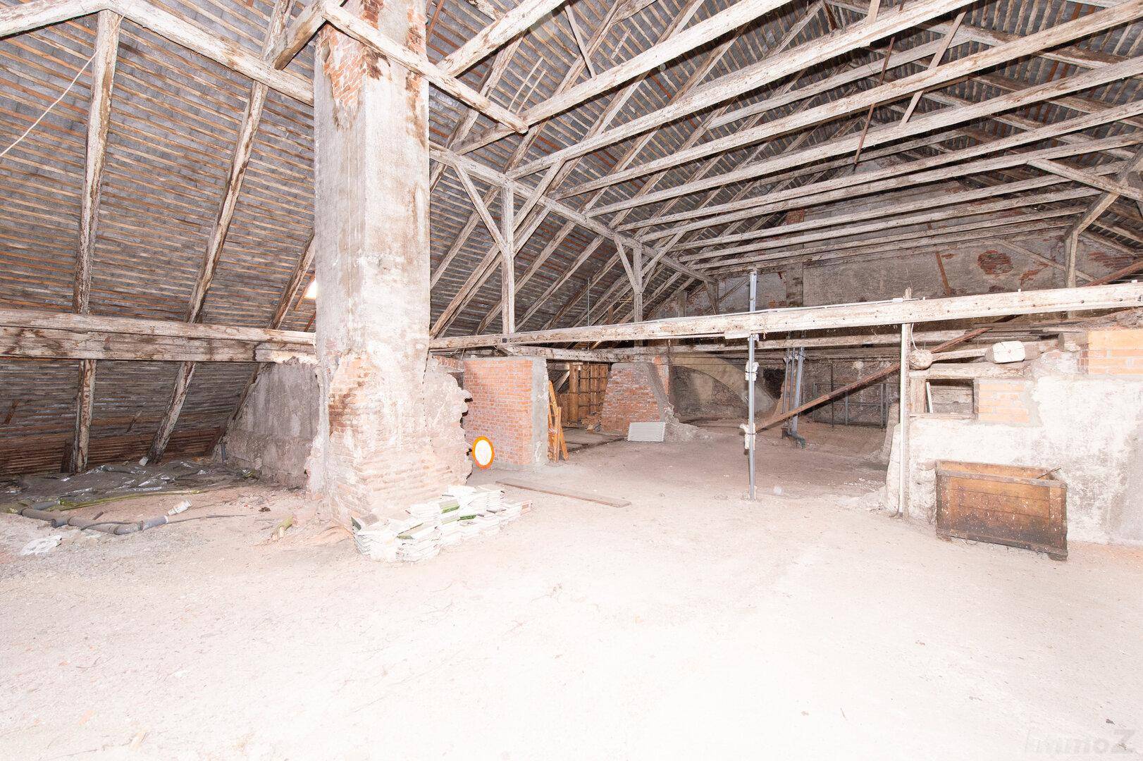 Großer Dachboden mit freiliegenden Holzbalken und Mauerwerk, ideal für einen Ausbau.