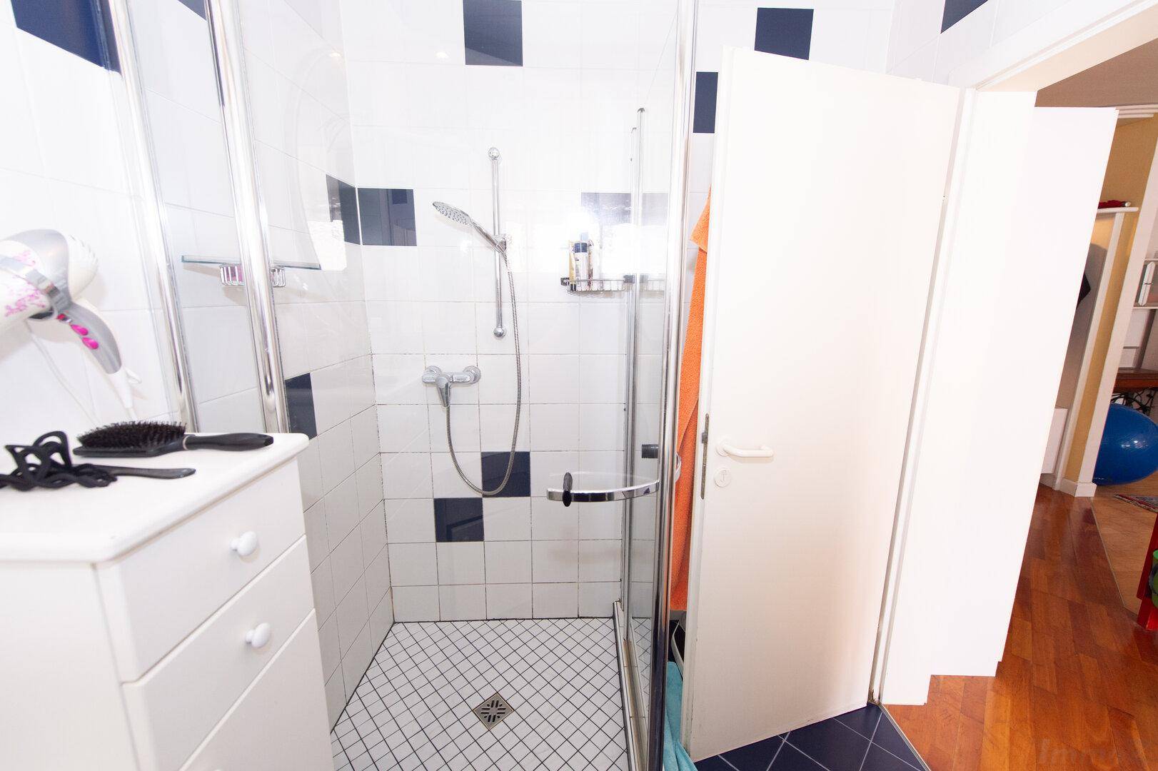 Nahaufnahme der Duschkabine im Badezimmer mit weißen und schwarzen Fliesen.