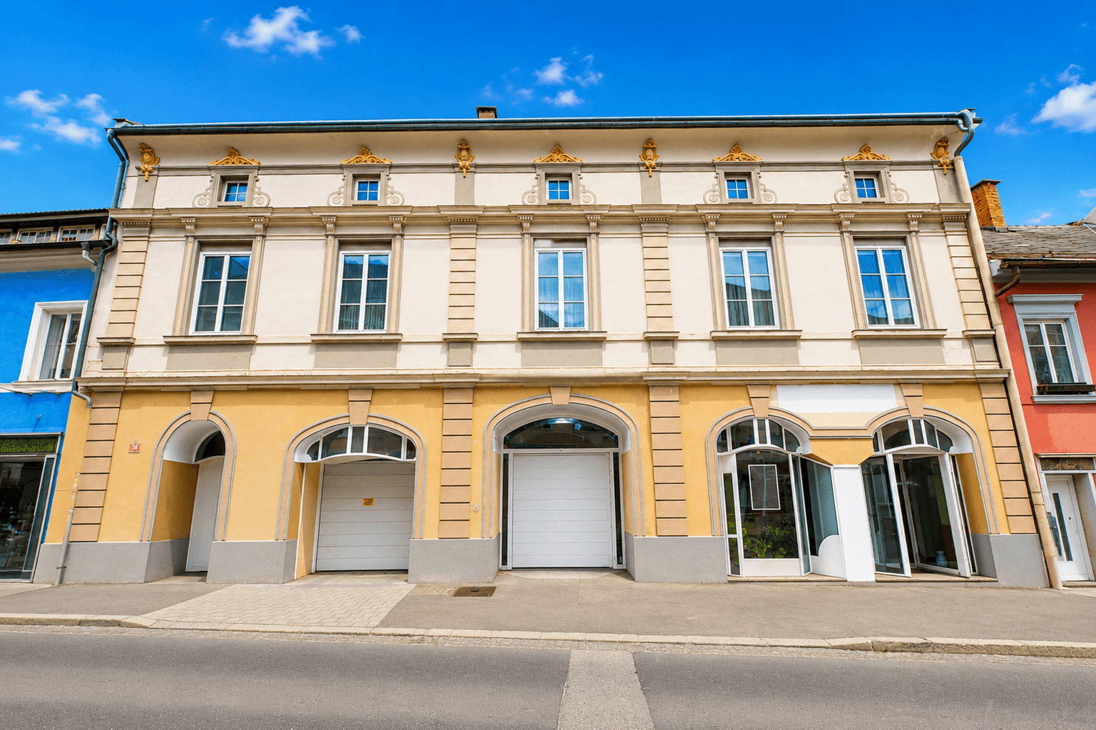 Historische Fassade eines Gebäudes mit mehreren Fenstern und Geschäftseingängen im Erdgeschoss.
