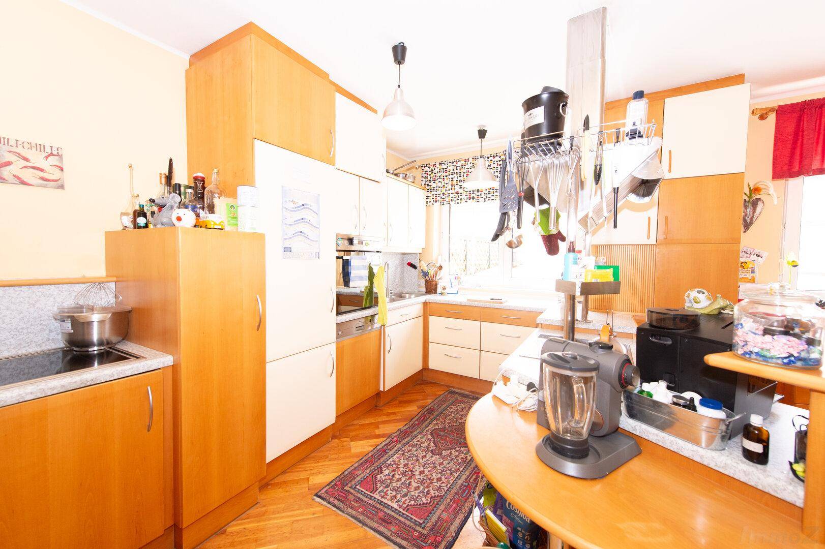 Funktionale Küche mit hellen Holzschränken, integrierten Geräten und einem kleinen Teppich.