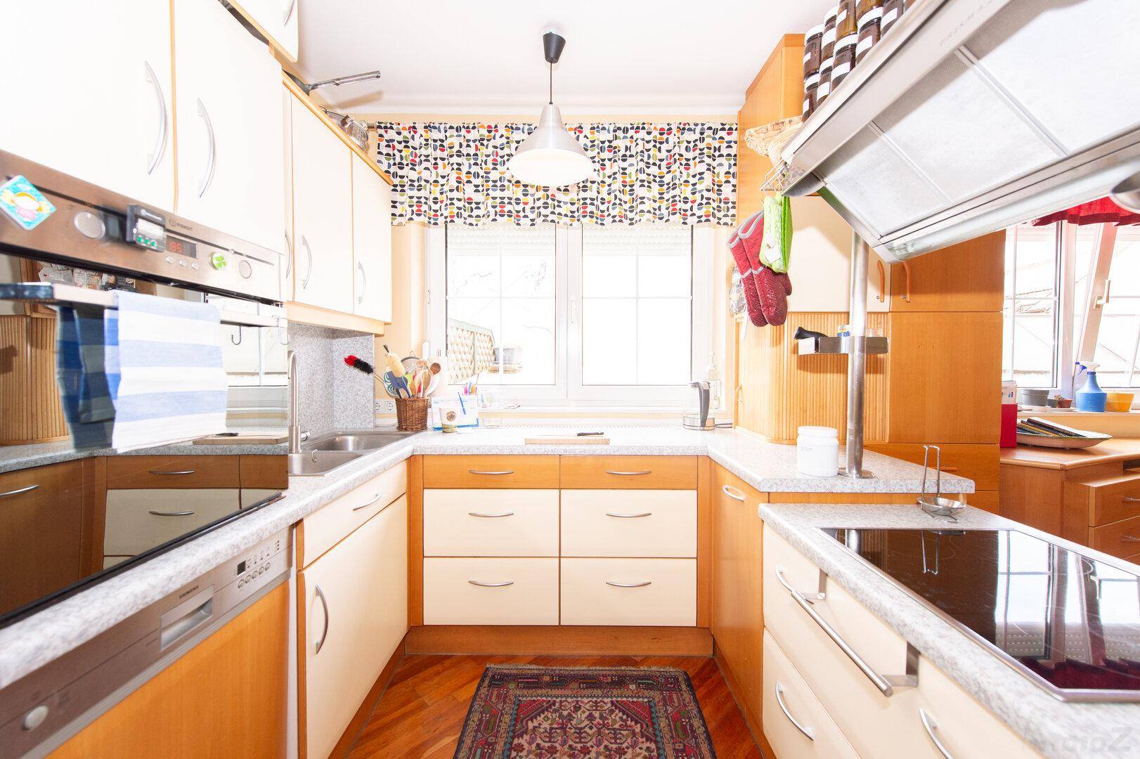 Helle Küche mit Fenster, Spülbecken, Geschirrspüler und Backofen, praktisch und gut ausgestattet.