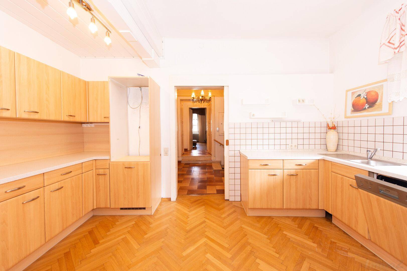 Küche mit U-förmiger Anordnung der Holzschränke und Blick in den angrenzenden Flur.