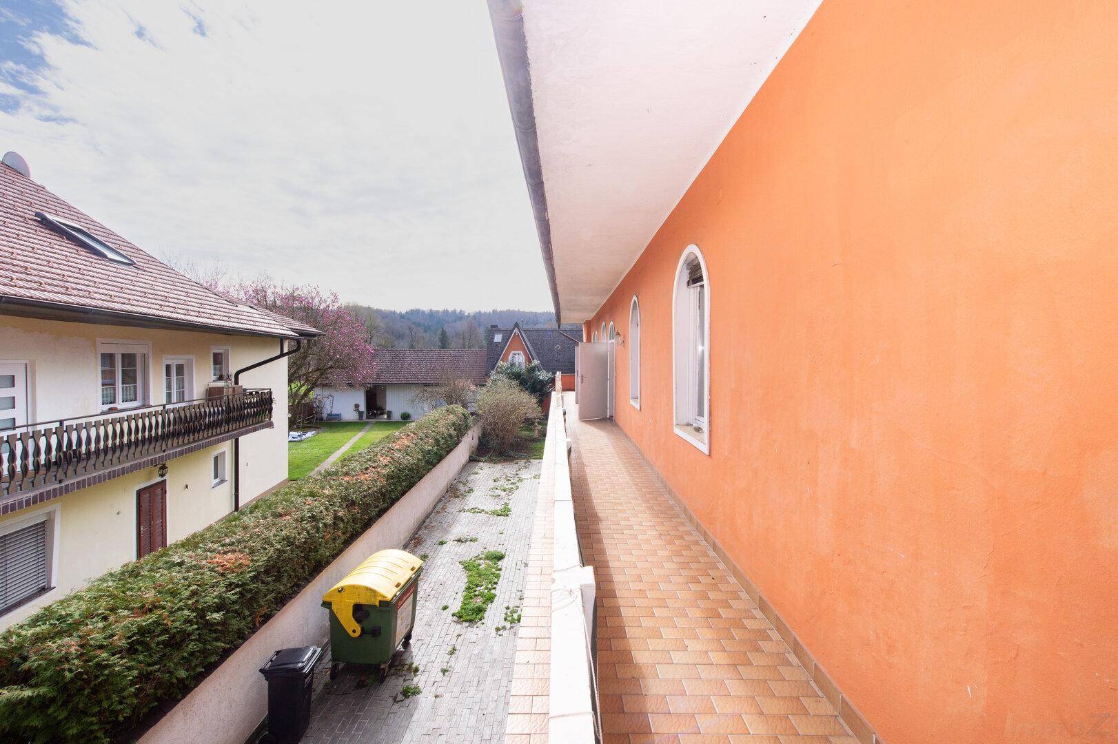 Langer Balkon mit Blick auf den Garten und die umliegenden Häuser.