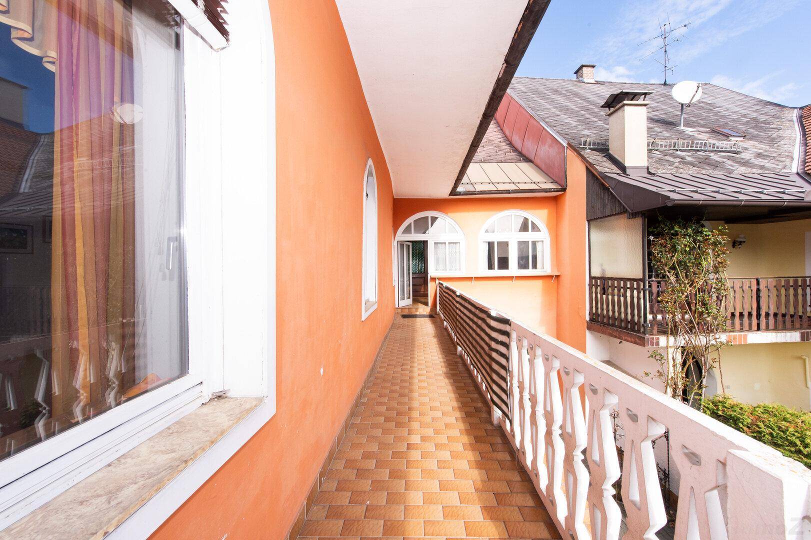 Langer, schmaler Balkon mit Terrakotta-Fliesen und Blick auf die Umgebung.