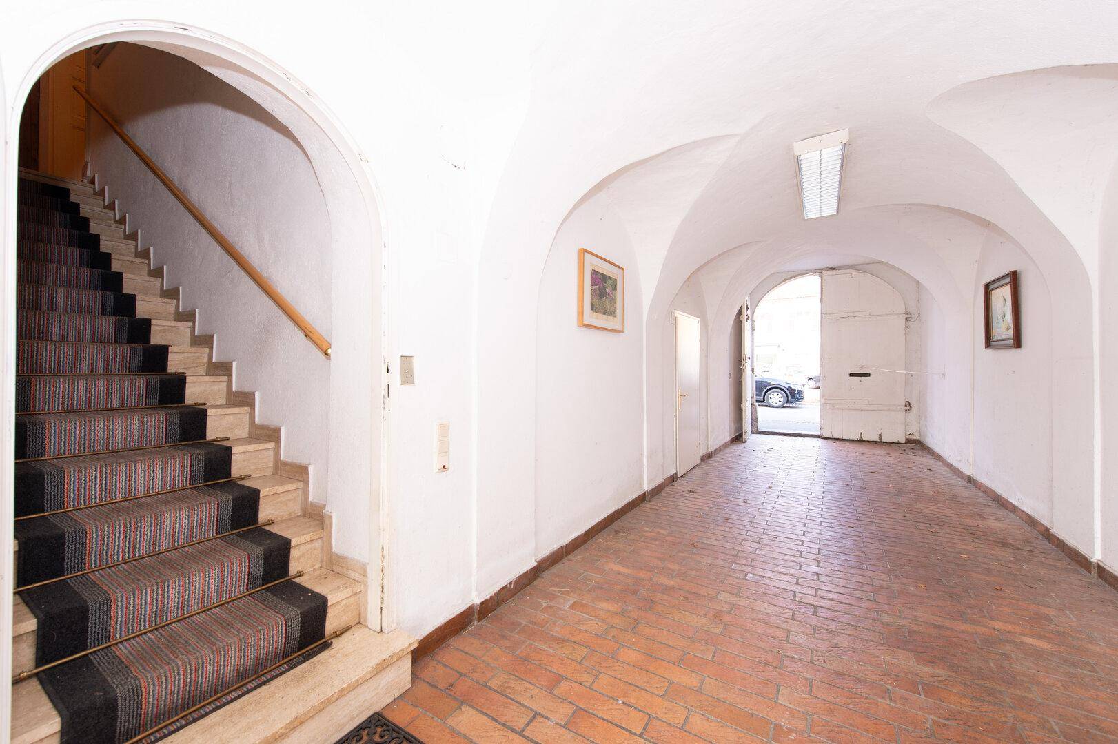 Gewölbter Eingangsbereich mit Ziegelboden und Treppe zu den oberen Etagen.