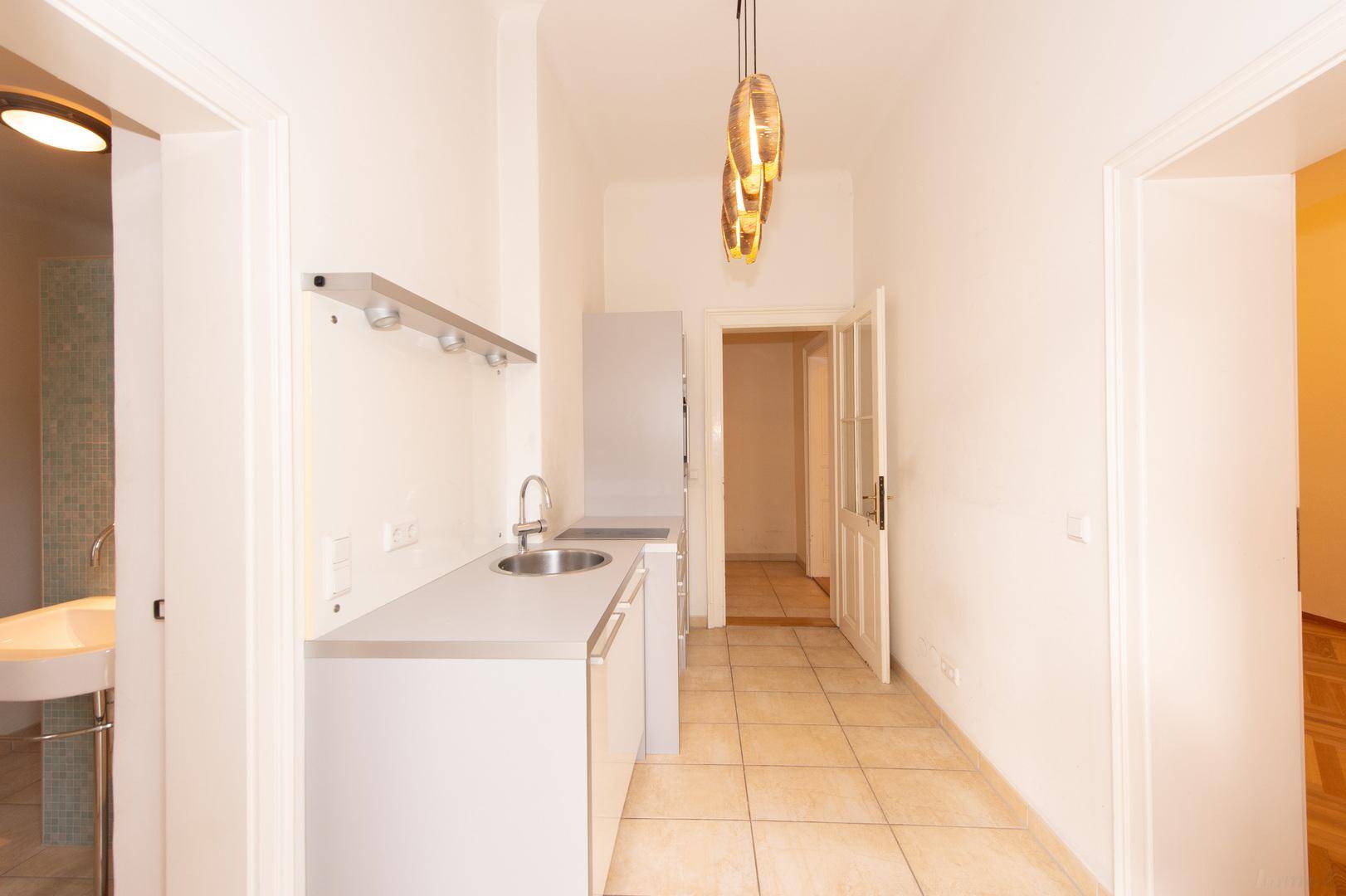 Heller Flur mit kleiner Küchenzeile und Zugang zu einem modernen Badezimmer.
