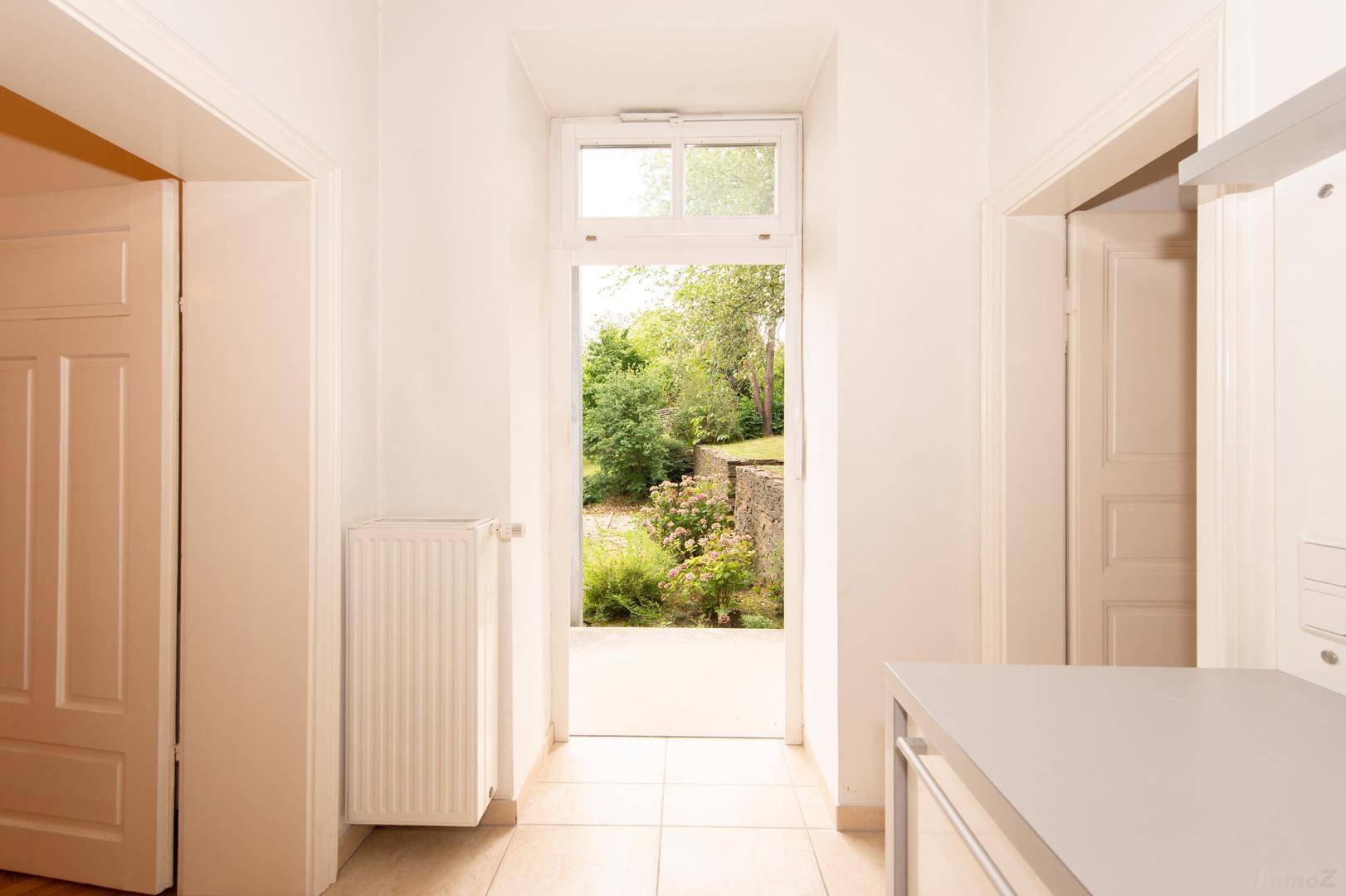 Heller Küchenbereich mit Blick und Zugang zum grünen Garten, ausgestattet mit Heizkörper.