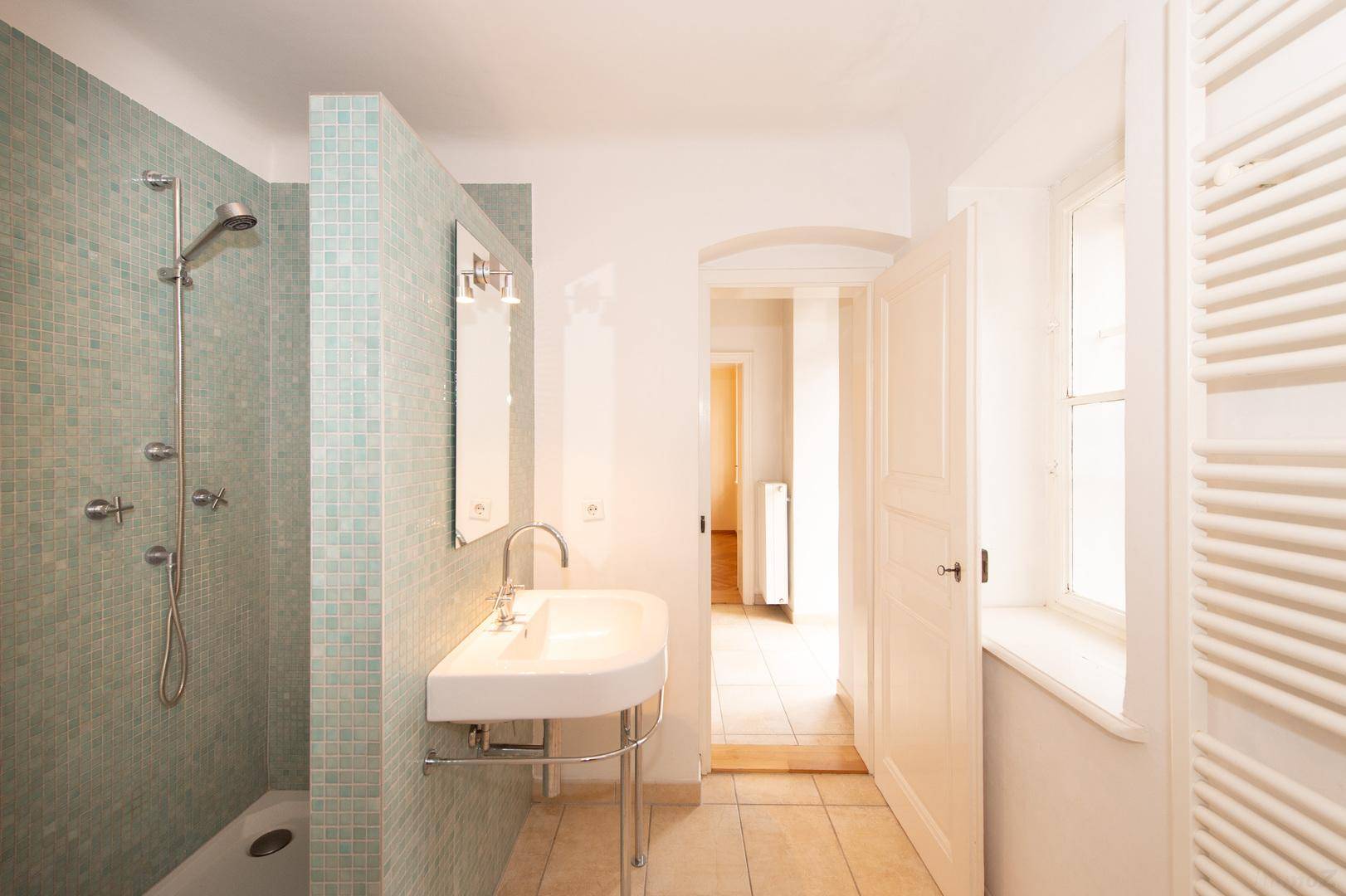 Modernes Badezimmer mit Duschbereich, Waschbecken und beheiztem Handtuchhalter.