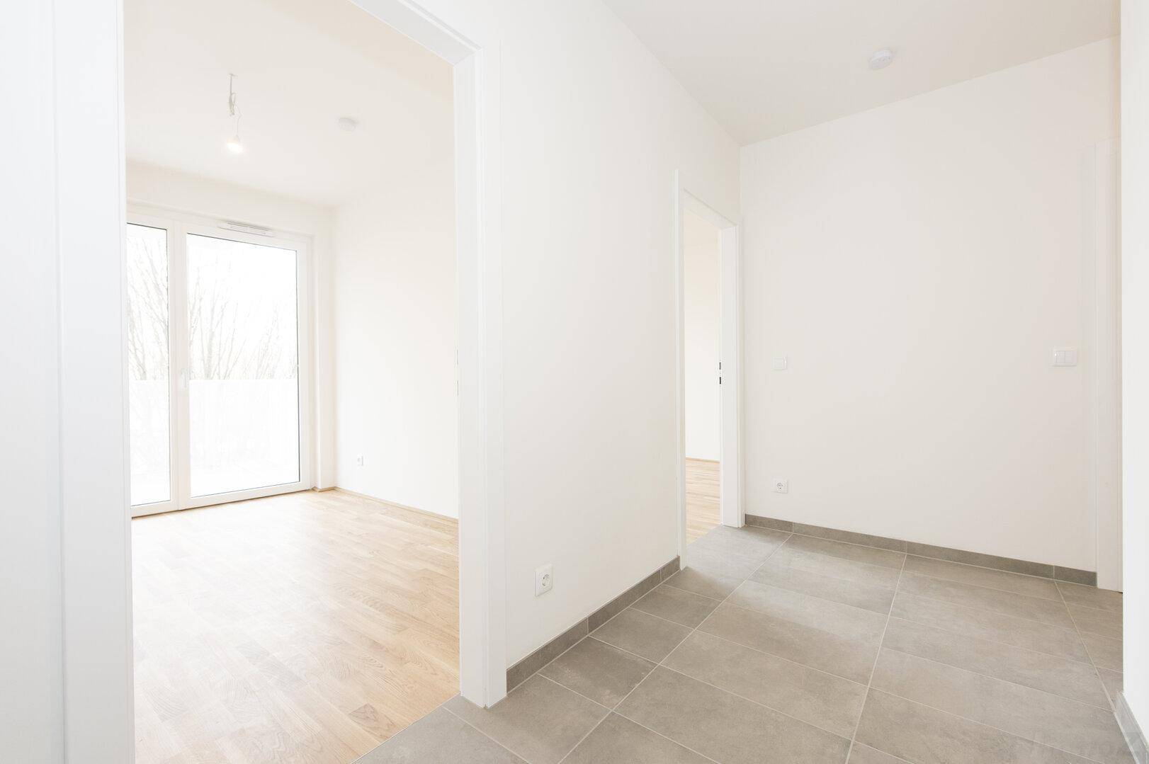 Heller Eingangsbereich mit Fliesenboden und Zugang zu weiteren Räumen sowie einem Balkon.