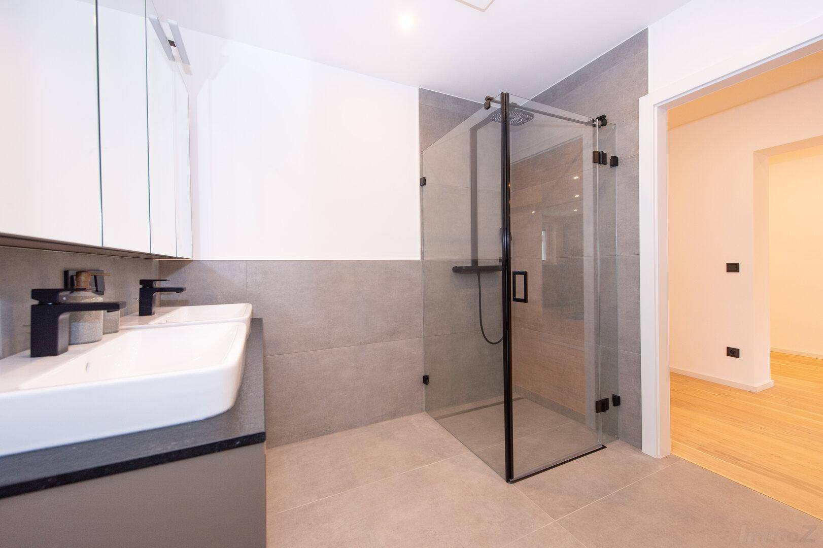 Elegantes Badezimmer mit begehbarer Dusche, Doppelwaschbecken und modernen Armaturen.