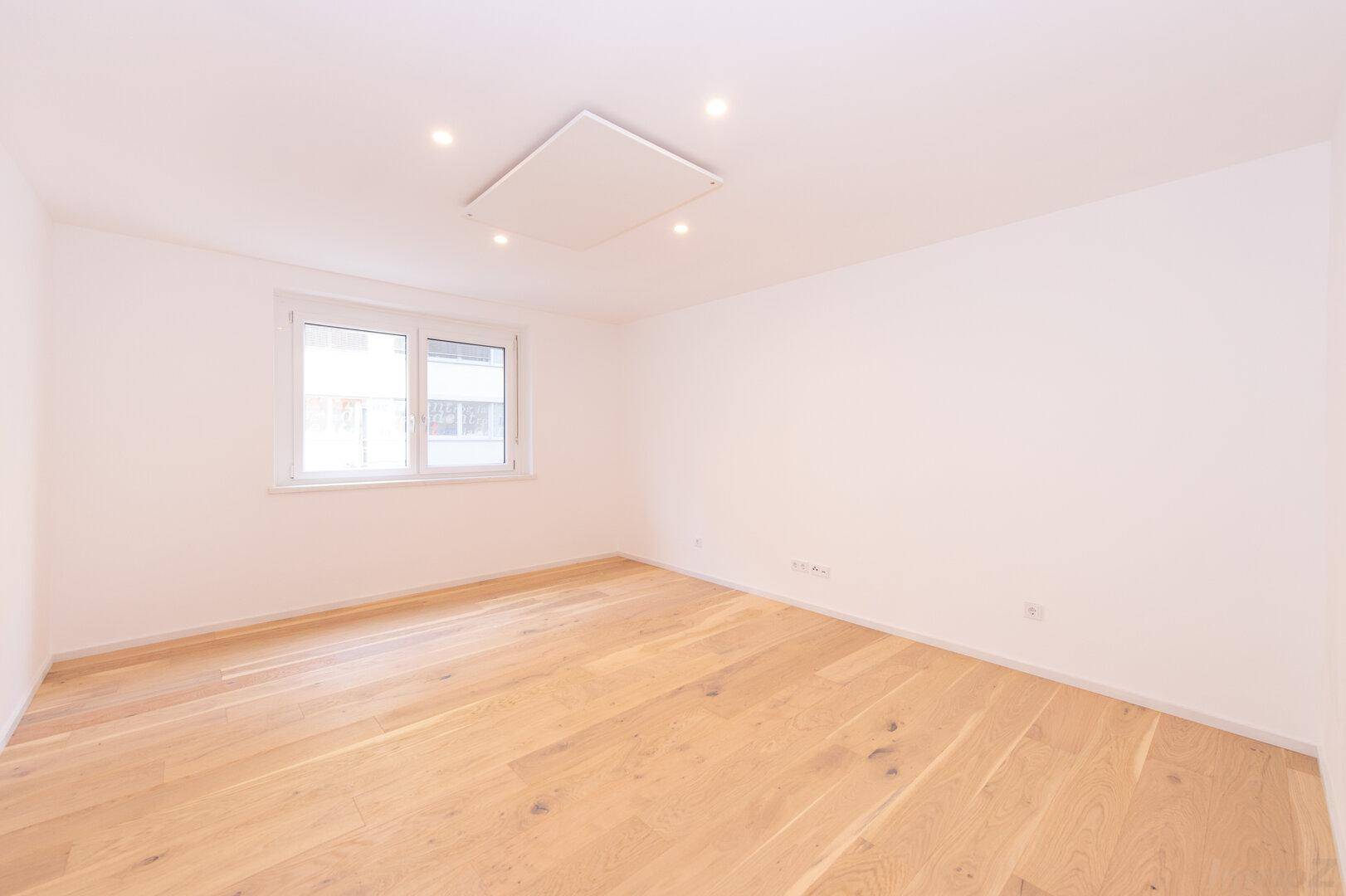 Geräumiges Schlafzimmer mit Holzboden und Fenster, das viel Tageslicht hereinlässt.