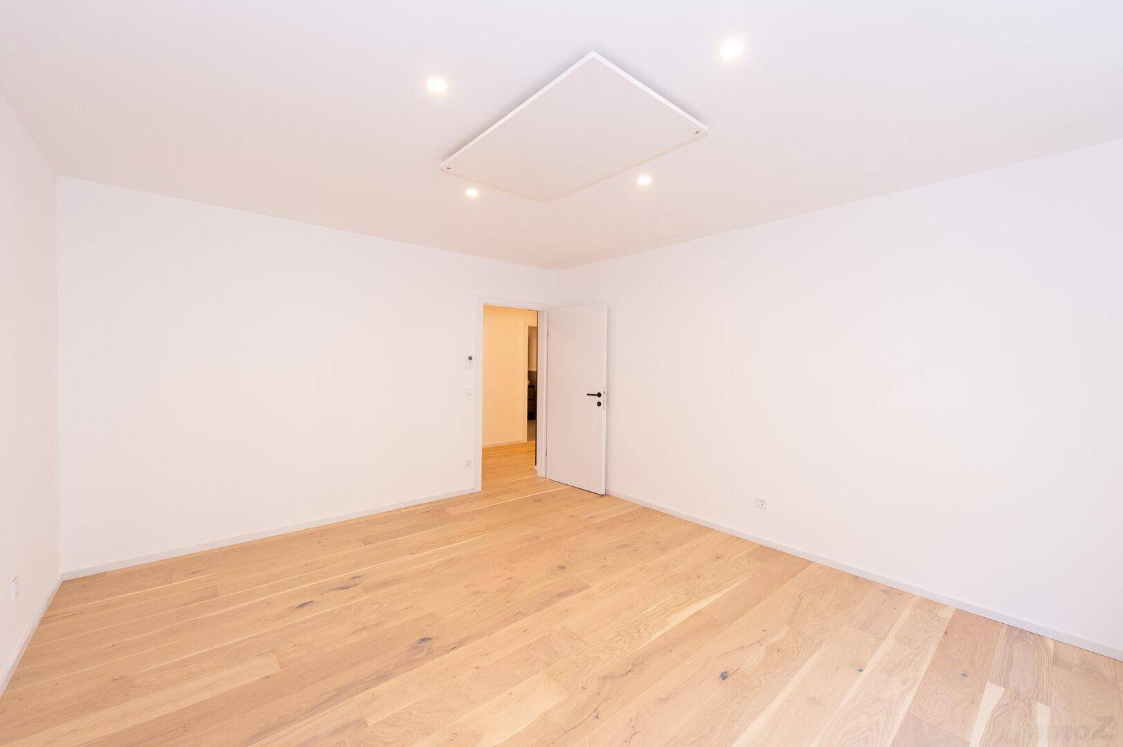 Leeres Schlafzimmer mit Holzboden und weiß gestrichenen Wänden, ideal für neue Einrichtung.