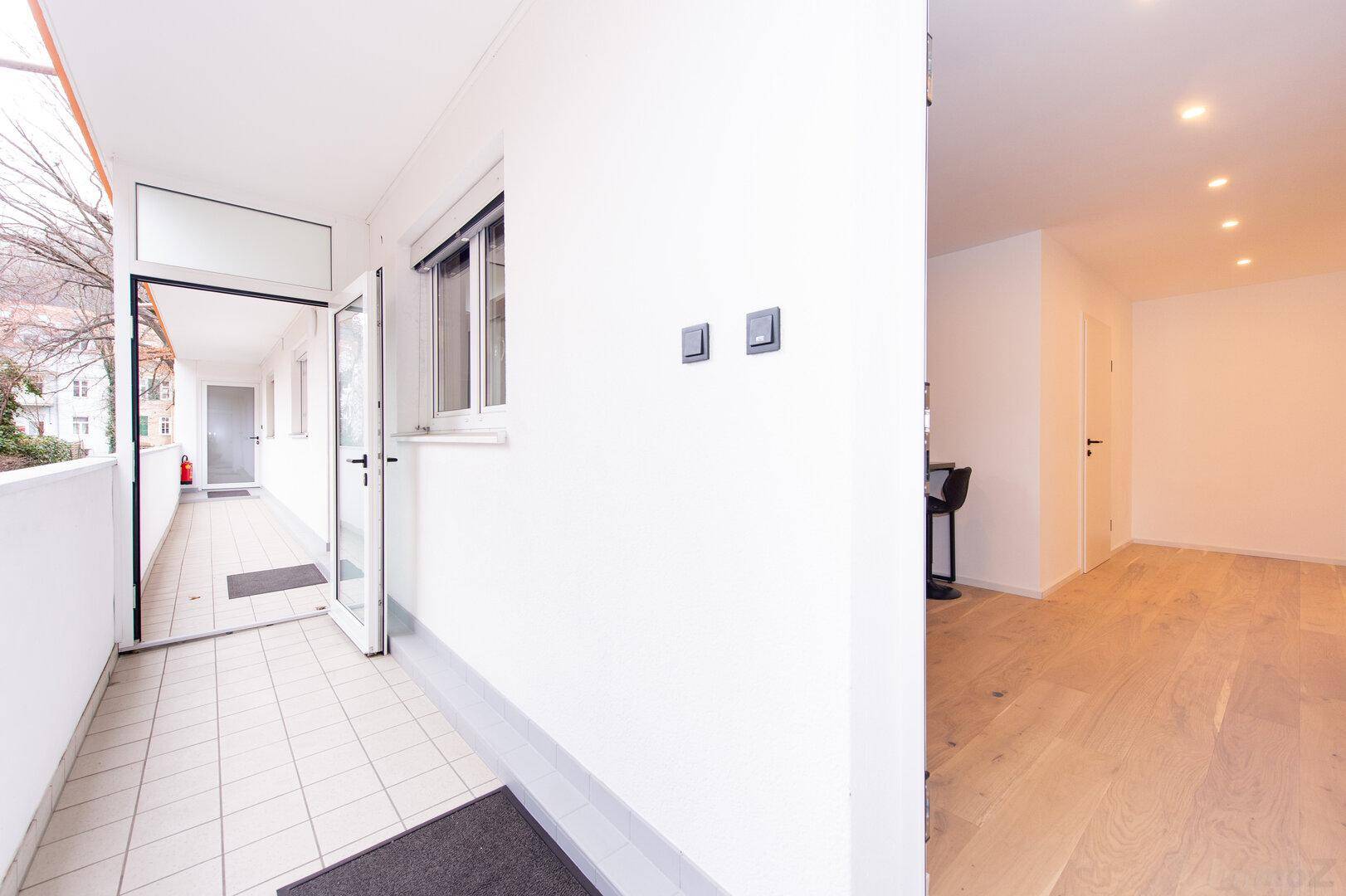Langer, gefliester Balkon mit Zugang zum Innenbereich und Blick auf die Umgebung.