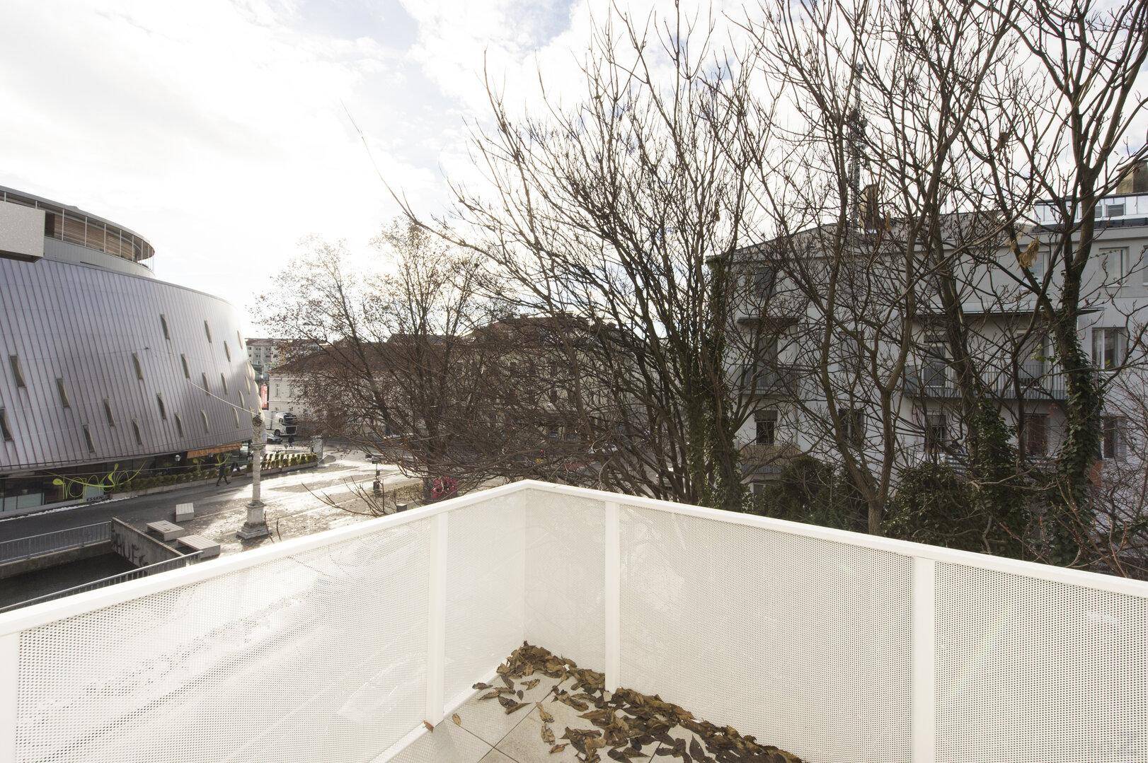 Blick vom Balkon auf die Straße und umliegende Gebäude mit kahlen Bäumen.