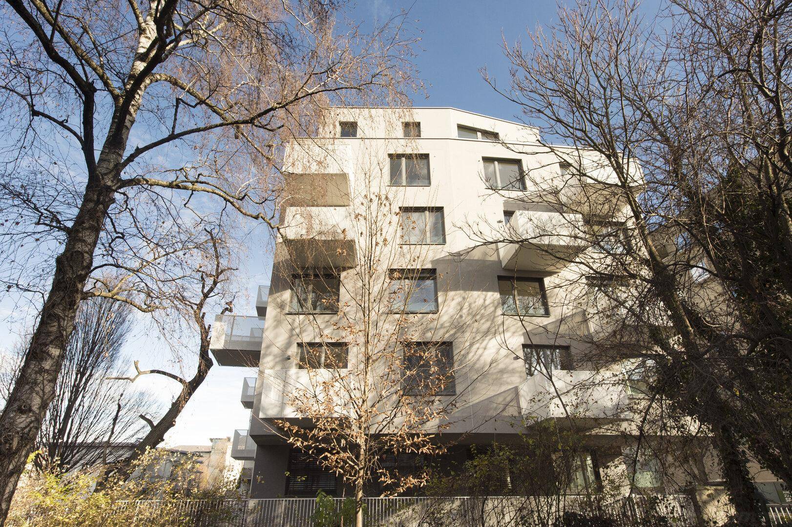 Moderne Architektur eines Mehrfamilienhauses mit mehreren Balkonen und großen Fenstern.