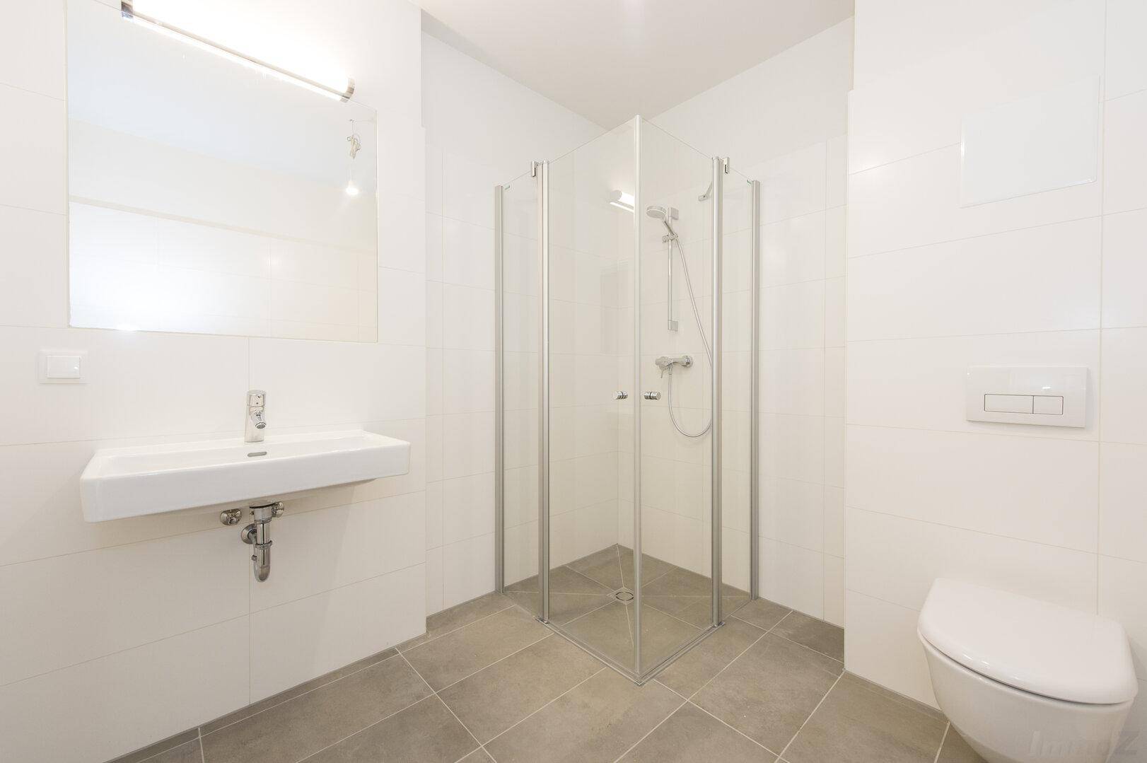 Modernes Badezimmer mit Waschbecken, Duschkabine und wandhängendem WC in hellen Farben.