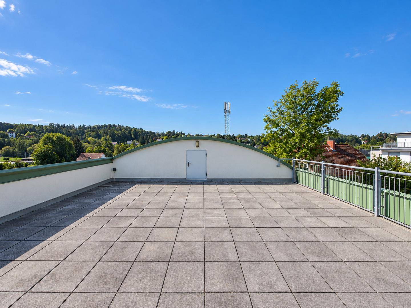 Weitläufige Dachterrasse mit Fliesenboden und Panoramablick auf die Umgebung.