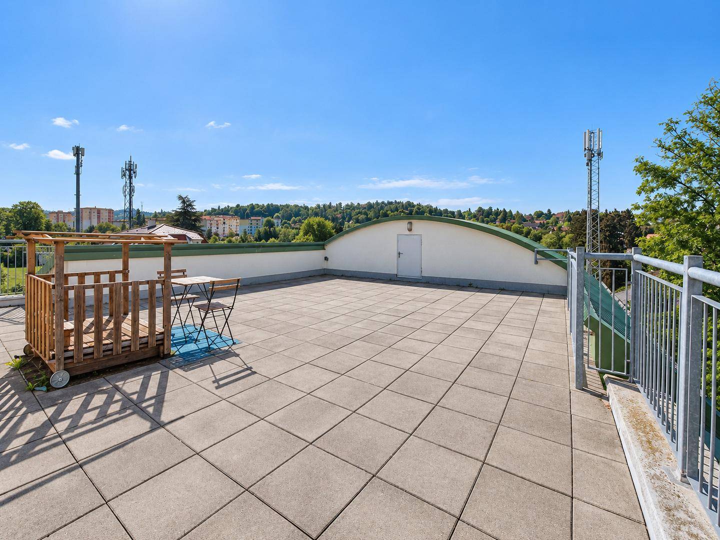 Sonniger Dachterrassenbereich mit Gartenmöbeln, Fliesenboden und weitem Ausblick.