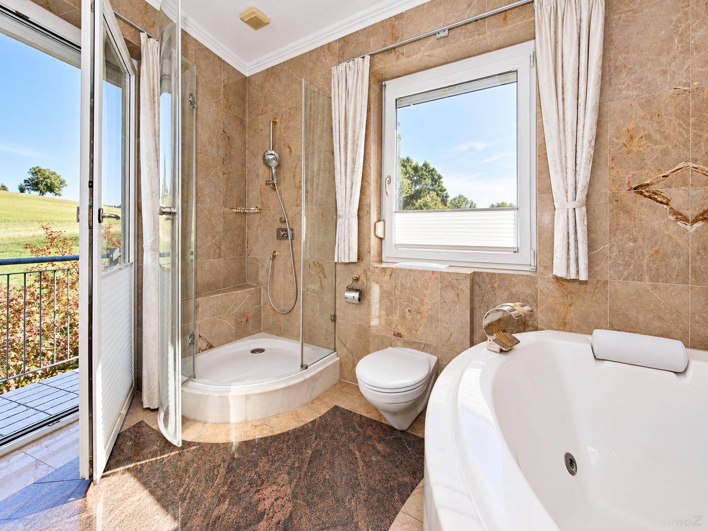 Stilvolles Badezimmer mit Dusche, WC und direktem Zugang zum Balkon mit Landschaftsblick.