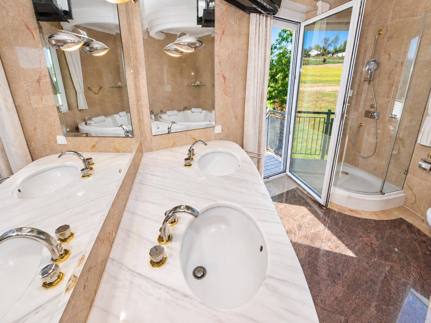 Exklusives Badezimmer mit Doppelwaschbecken, großen Spiegeln und Zugang zum Außenbereich.