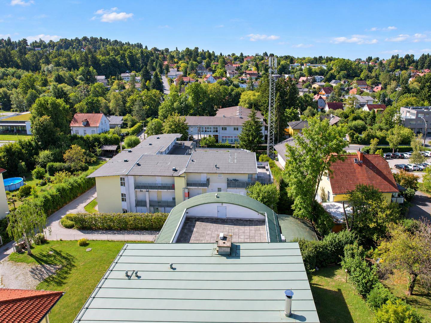 Weitläufige Luftaufnahme der Immobilie und ihrer grünen Umgebung mit weiteren Häusern.