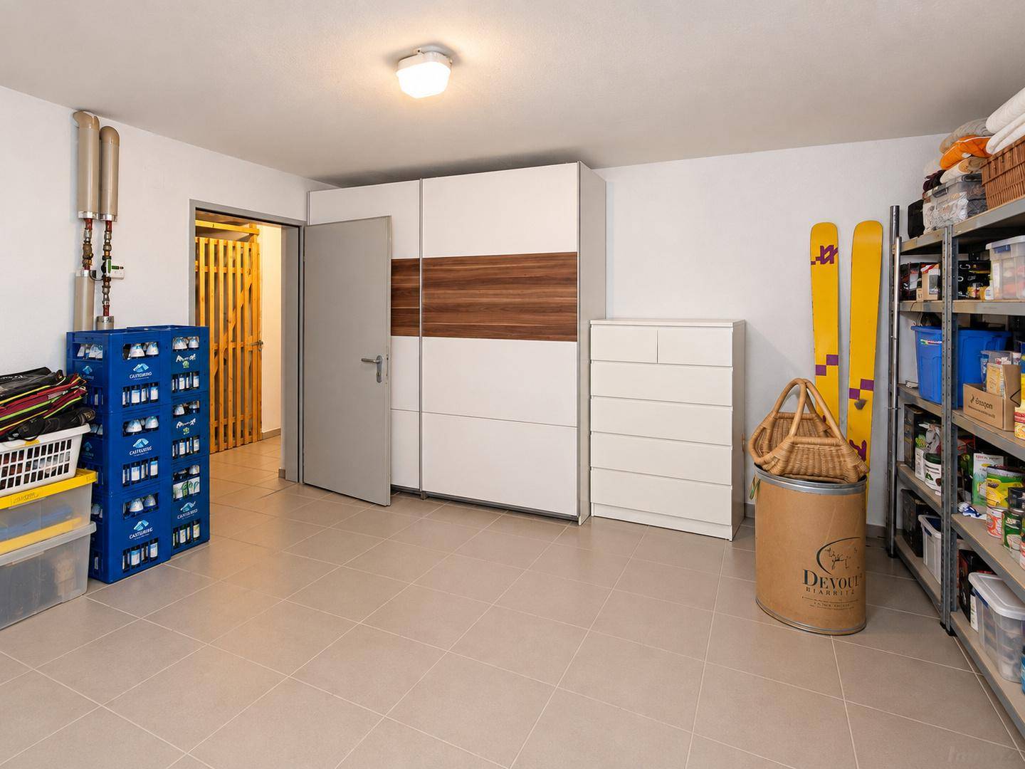 Kellerraum mit Regalen, Kleiderschrank und Zugang zu weiteren Lagerbereichen.
