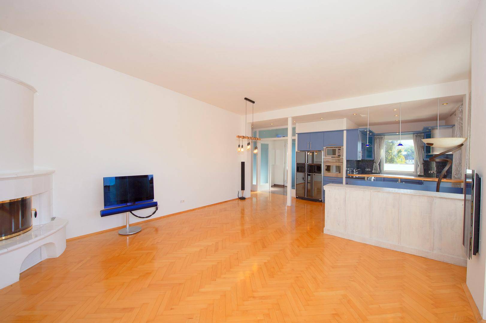 Offener Wohnbereich mit Parkettboden, Kamin und Blick auf die moderne Küche.