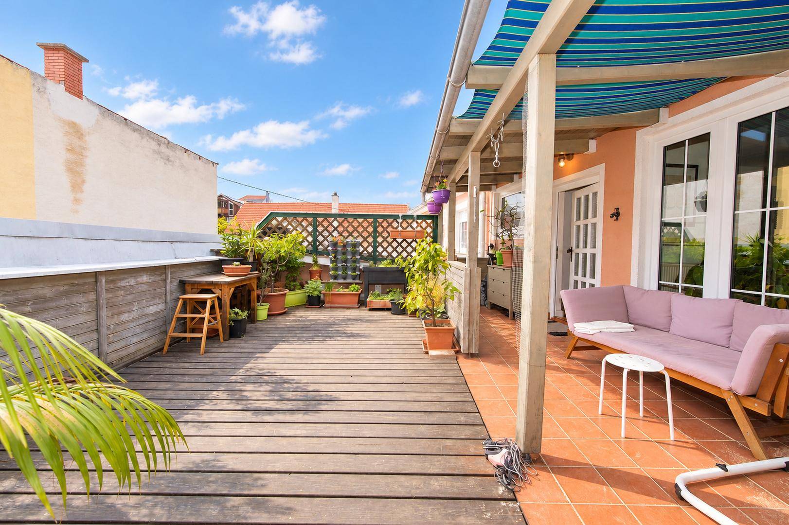 Geräumige Terrasse mit Holzdeck, Markise und bequemen Gartenmöbeln.