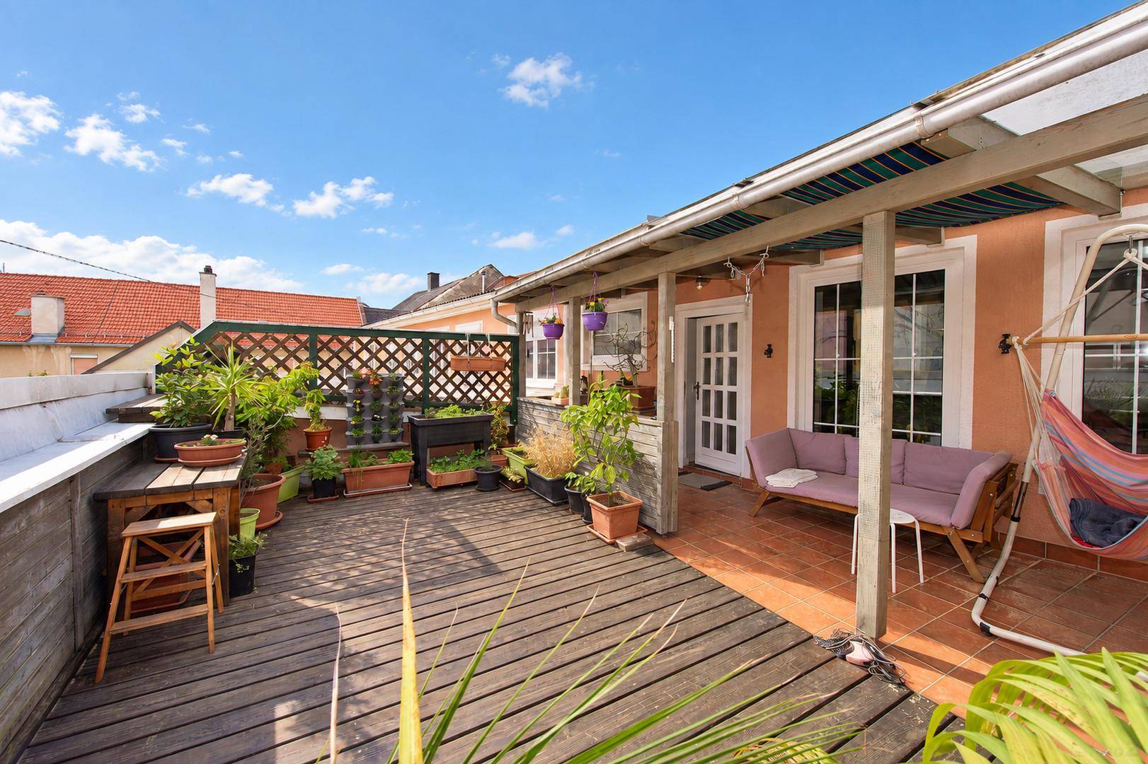 Große Dachterrasse mit Holzdeck, vielen Pflanzen und einer Hängematte zum Entspannen.