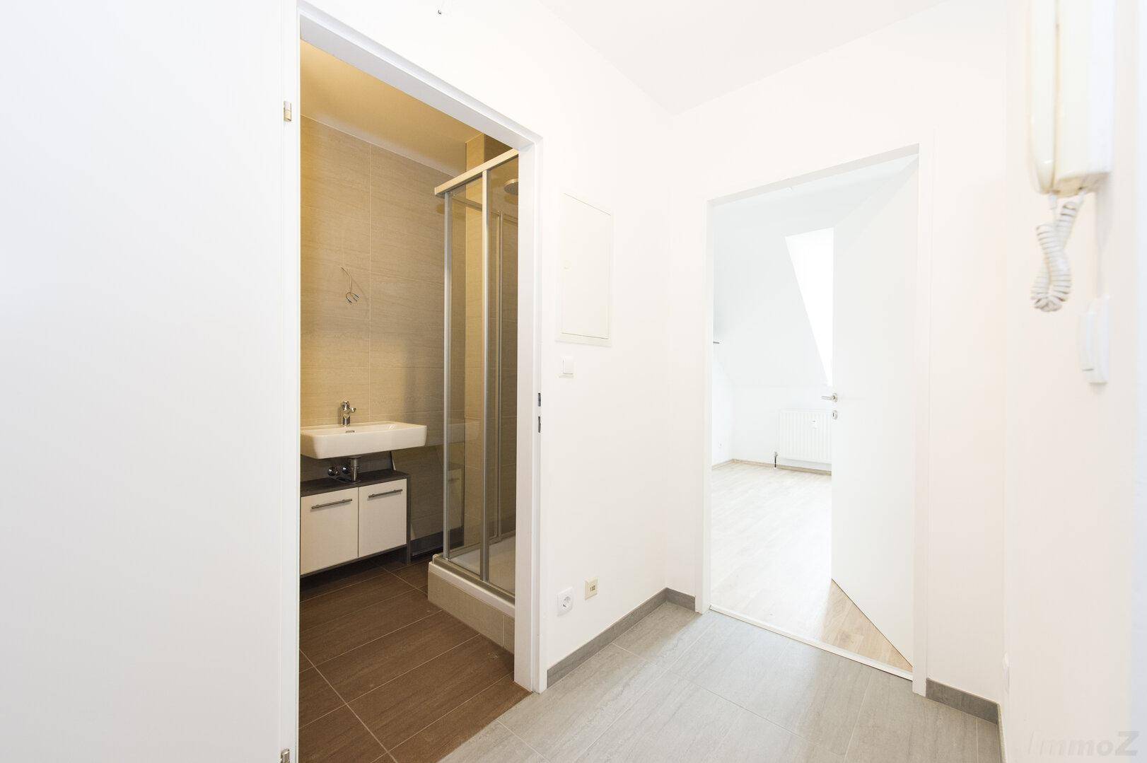 Heller Flur mit Zugang zu einem Badezimmer und einem weiteren Wohnraum.