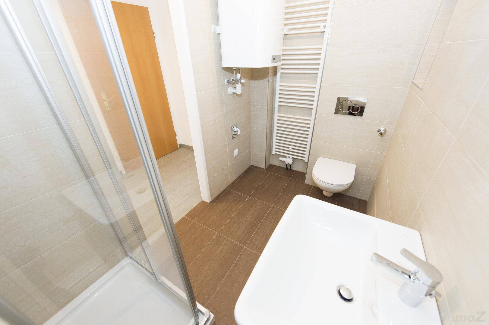 Helles Badezimmer mit Dusche, WC, Waschbecken und beheiztem Handtuchhalter.
