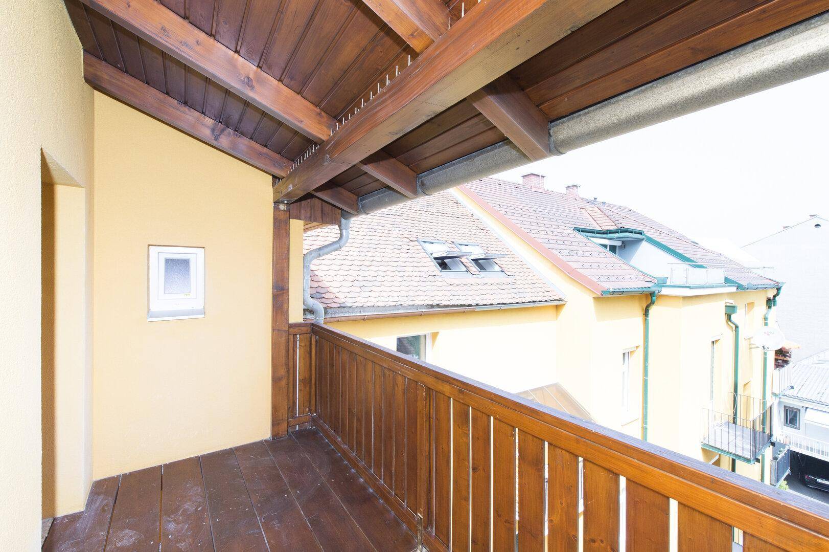 Überdachter Holzbalkon mit Blick auf die umliegenden Dächer und Gebäude.