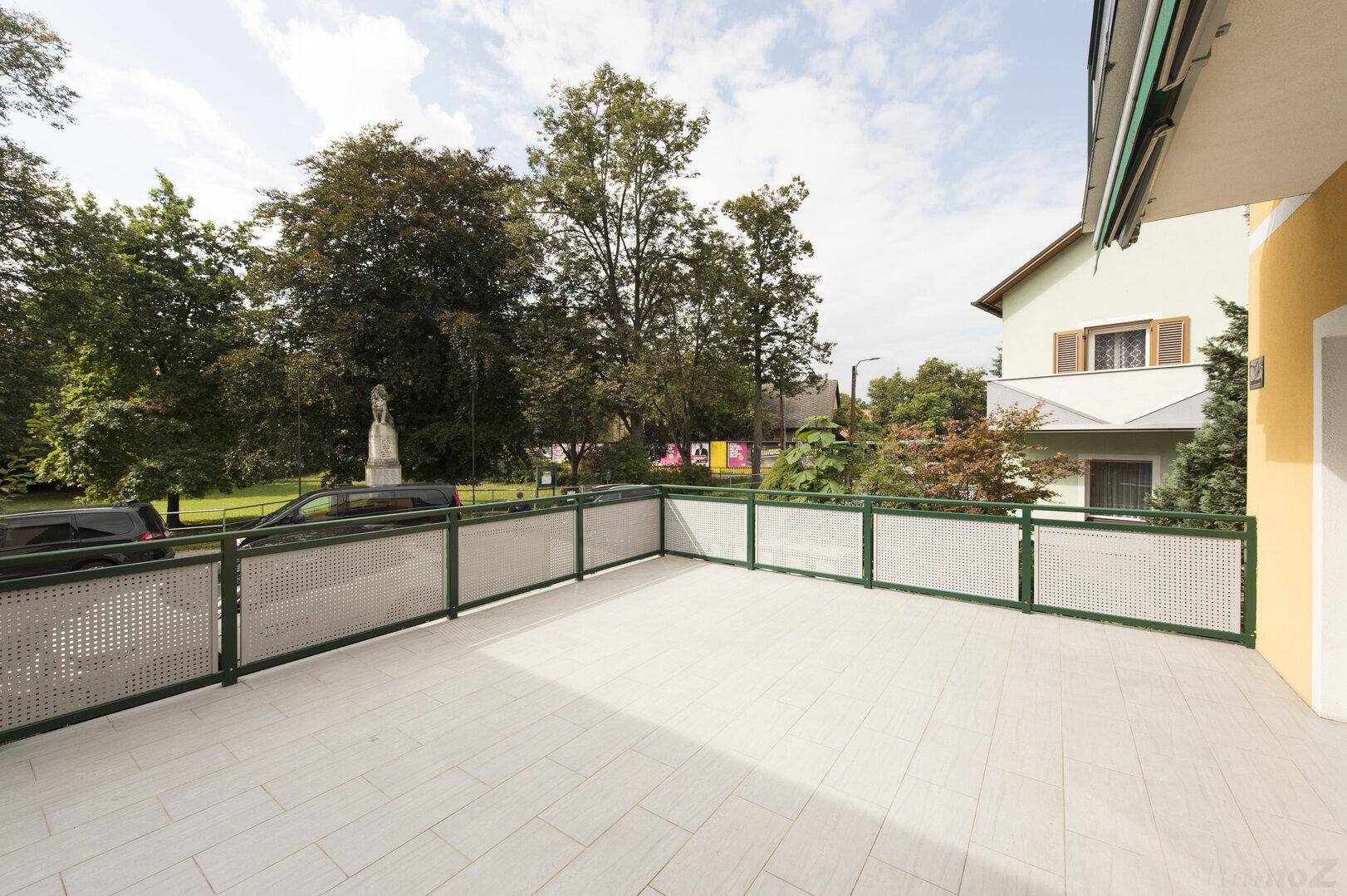 Weitläufige Terrasse mit Blick auf grüne Bäume und die ruhige Wohngegend.