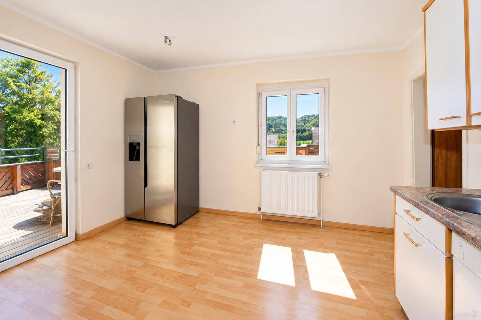 Helle Küche mit Platz für Essbereich, großem Kühlschrank und Zugang zur Außenterrasse.