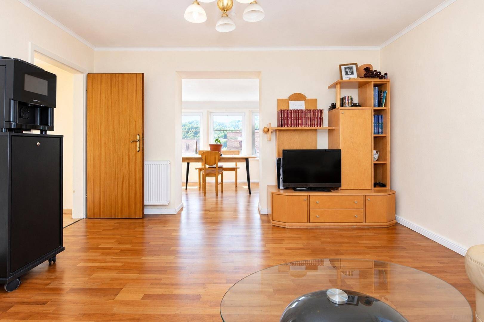 Wohnzimmer mit Laminatboden und Blick in den angrenzenden Essbereich, ausgestattet mit TV-Möbeln.