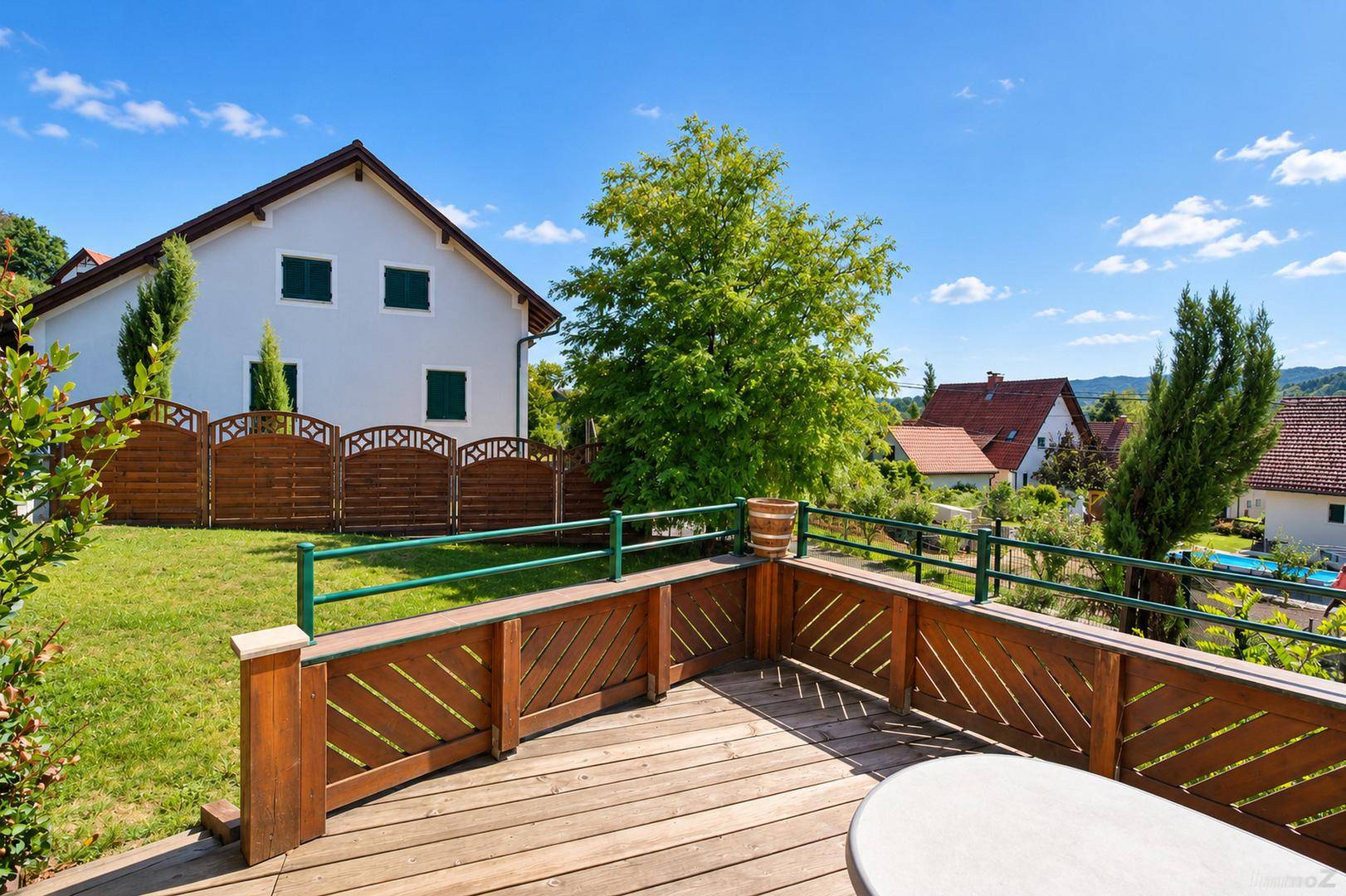 Geräumige Holzterrasse mit Blick auf den Garten und die umliegende Wohnsiedlung.