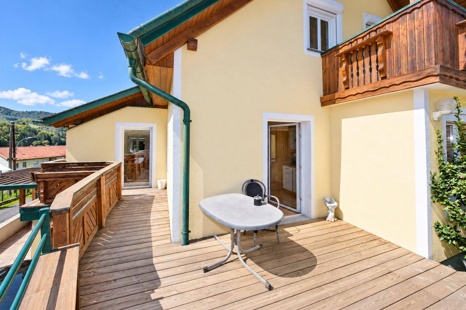Sonniger Terrassenbereich mit Holzboden und kleinem Tisch, ideal für entspannte Stunden im Freien.