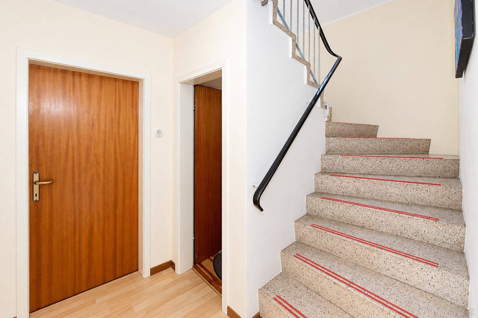 Flur mit Treppe zum Obergeschoss, Holztüren und Laminatboden, funktional gestaltet.