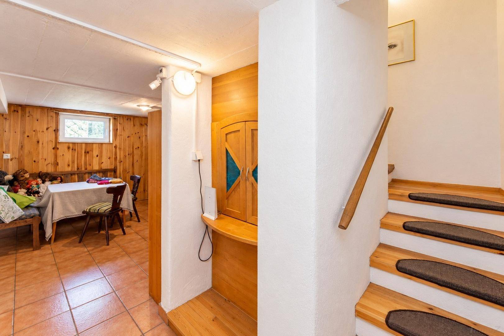 Treppenabgang zum Kellerbereich mit Holzverkleidung und Fliesenboden, bietet zusätzlichen Wohnraum.