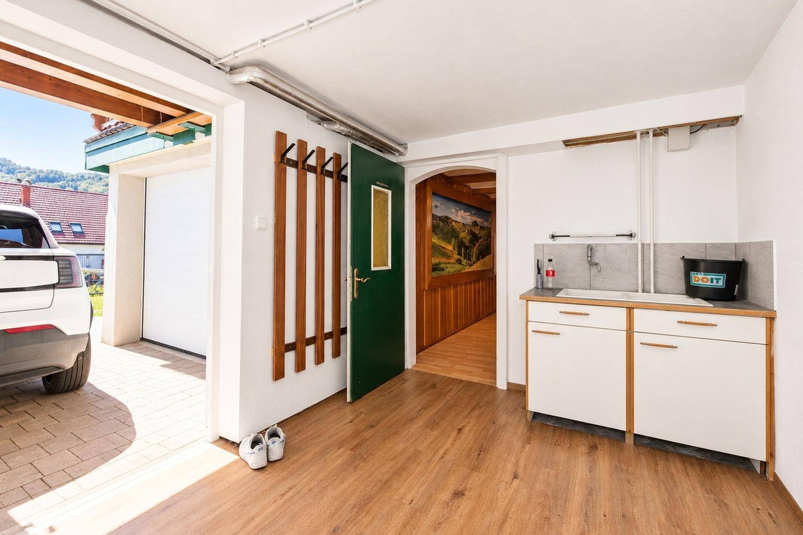 Garagenzugangsbereich mit kleiner Küchenzeile, Garderobe und direktem Zugang zum Außenbereich.