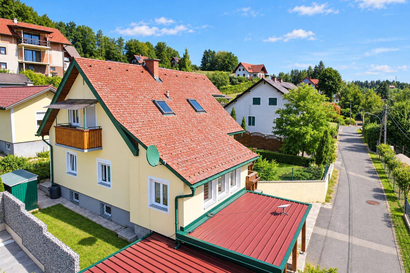 Luftaufnahme des Hauses mit rotem Ziegeldach und Gaubenfenstern, umgeben von weiteren Wohnhäusern.